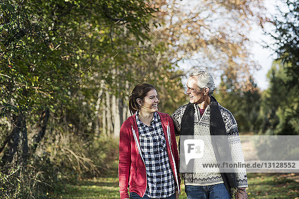 Mann und Enkelin unterhalten sich beim Spaziergang auf dem Feld inmitten von Bäumen