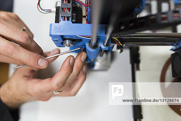 Beschnittene Hände eines Ingenieurs fixieren 3D-Drucker auf Tisch