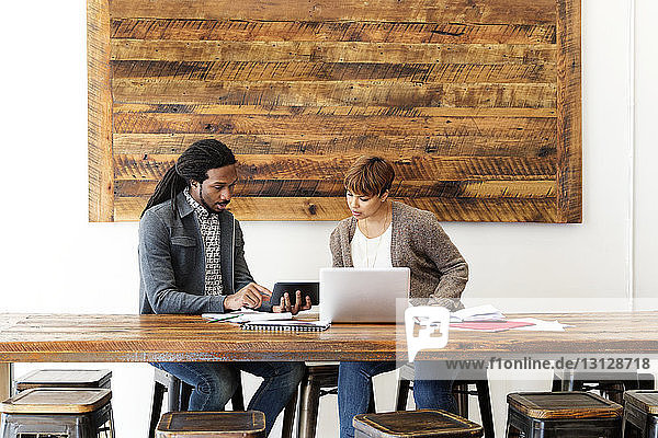 Kreative Geschäftskollegen nutzen Laptop-Computer  während sie im Büro am Konferenztisch sitzen