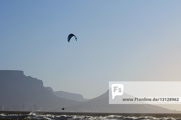 Mann kitesurft auf dem Meer bei klarem Himmel