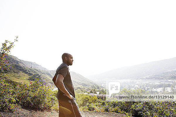 Seitenansicht eines Mannes  der die Landschaft betrachtet  während er auf einem Berg vor klarem Himmel steht