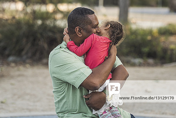 Vater umarmt Tochter auf Spielplatz