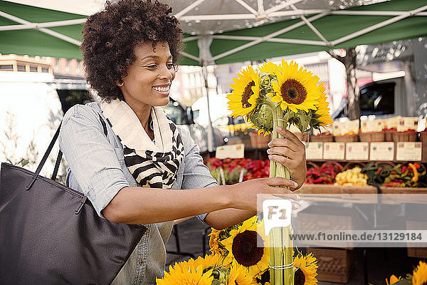 Frau kauft Sonnenblumen am Marktstand