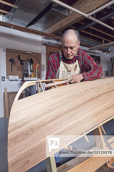Älterer Mann beim Bootsbau in der Werkstatt