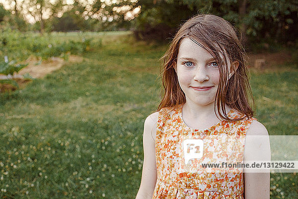 Portrait of smiling girl standing on grassy field at farm
