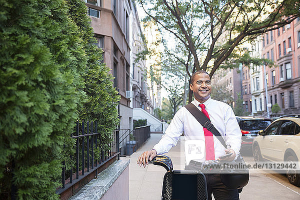 Happy businessman looking away while standing with bicycle on footpath