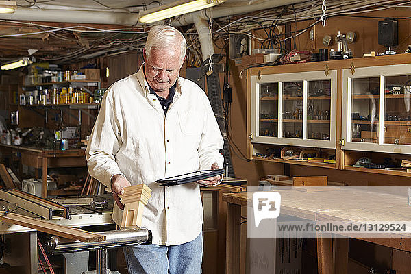 Carpenter using tablet computer in workshop