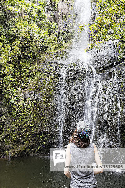 Rückansicht einer Wanderin mit Blick auf den Wasserfall