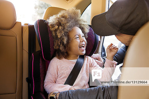 Lächelnde Tochter schaut den Vater an  während sie im Auto sitzt