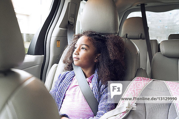 Thoughtful girl looking through window while traveling in car
