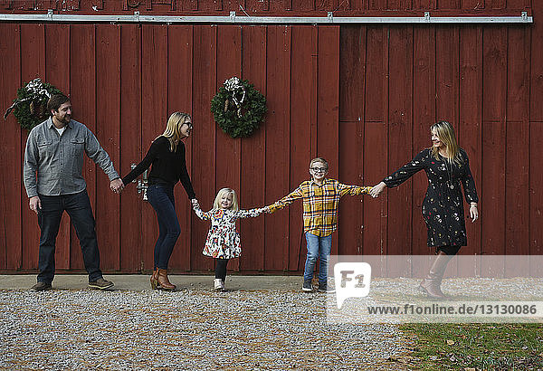 Happy family holding hands while standing at yard
