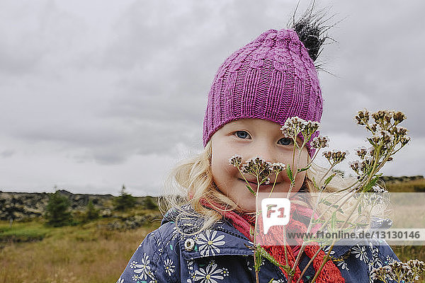 Porträt eines süßen Mädchens mit Wildblumen auf dem Feld