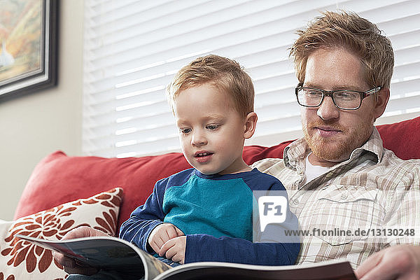 Niedriger Blickwinkel von Sohn und Vater beim Lesen von Büchern zu Hause
