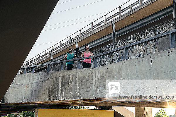 Tiefblick auf ein junges Paar  das gemeinsam auf der Brücke joggt