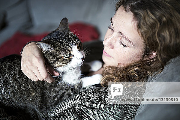 Hochwinkelansicht einer Frau mit Katze  die sich zu Hause auf dem Sofa entspannt