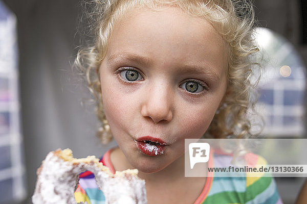 Portrait of cute girl making face while eating donut