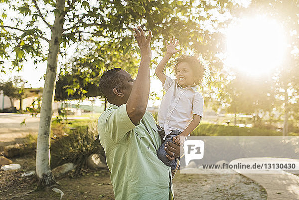 Happy son giving high-five to father at park