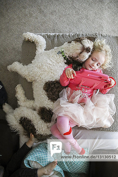 High angle view of sisters with dog lying on bed