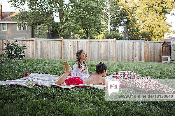 Geschwister entspannen sich im Hinterhof auf einer Decke