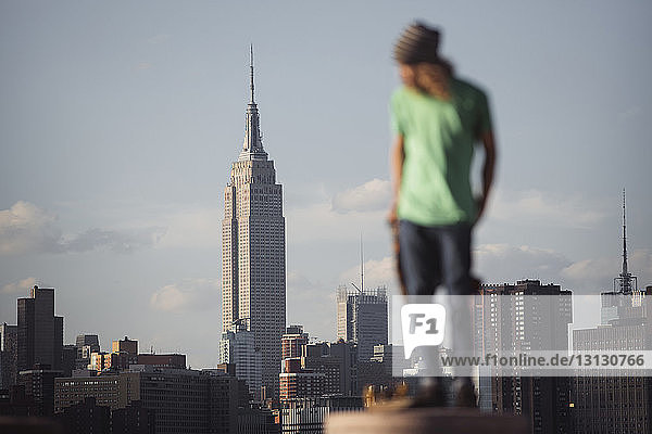 Man standing on column with empire state building in background