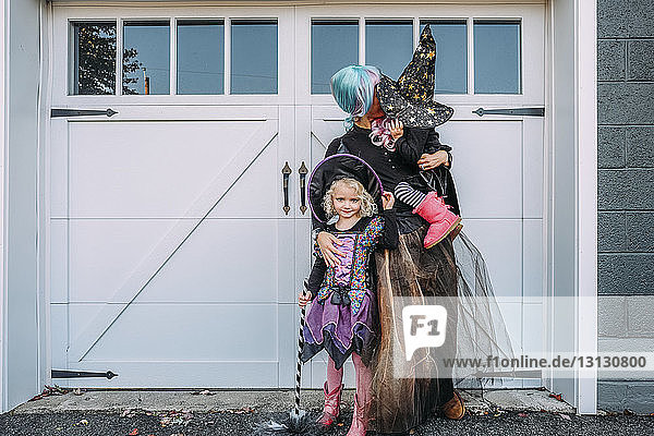 Mutter mit Töchtern in Halloween-Kostümen an der Tür stehend