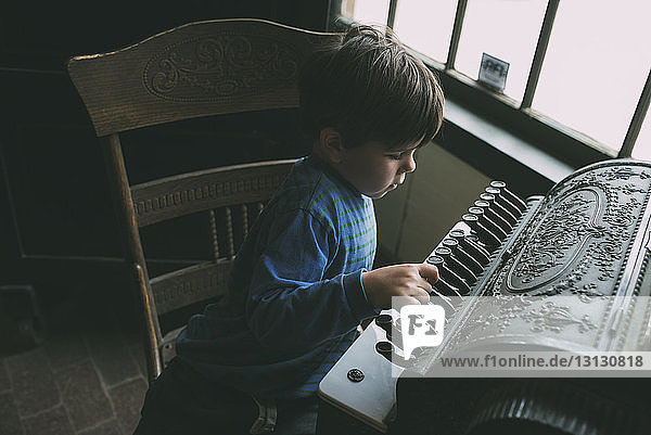 High angle view of boy playing musical instrument at home