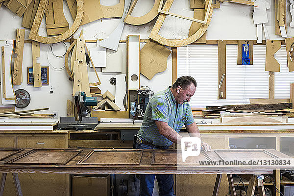 Carpenter polishing wood while working at workshop