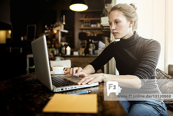 Young woman using laptop at cafe