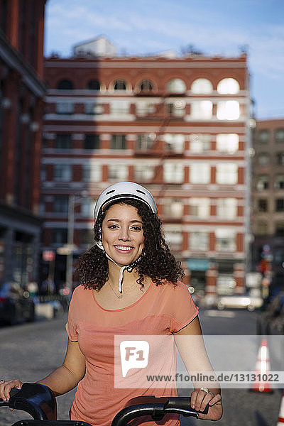 Portrait of happy businesswoman holding bicycle on street
