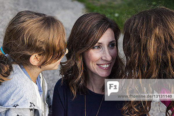 Schrägaufnahme von glücklichen Töchtern  die im Freien stehend mit der Mutter sprechen