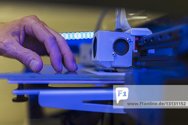 Geschnittene Hand eines Ingenieurs  der einen 3D-Drucker im Büro untersucht