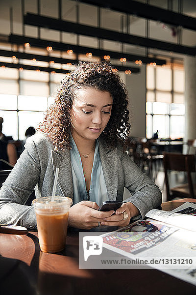 Geschäftsfrau benutzt Smartphone am Café-Tisch