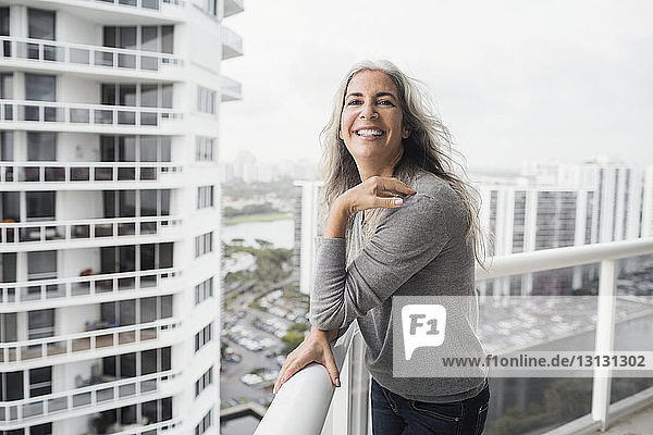 Porträt einer glücklichen reifen Frau auf dem Balkon stehend