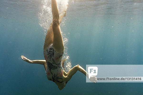 Woman swimming upside down in sea