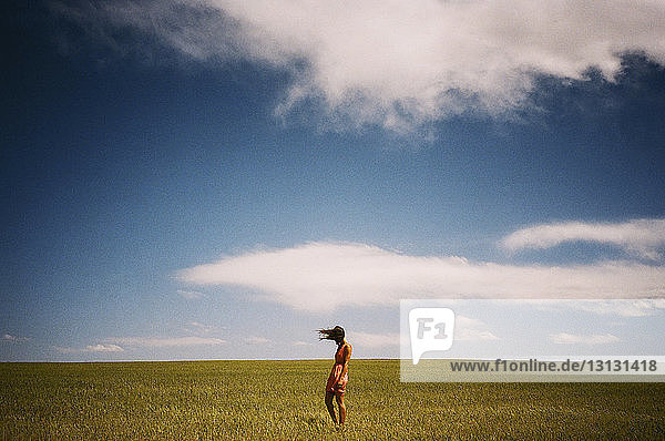 Frau steht auf Grasfeld gegen den Himmel