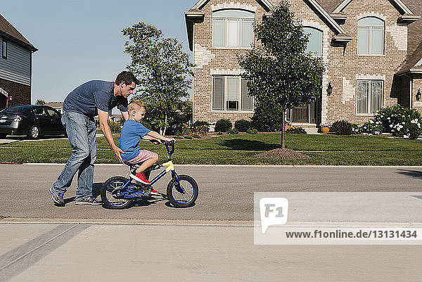 Vater hilft Sohn beim Fahrradfahren auf der Straße
