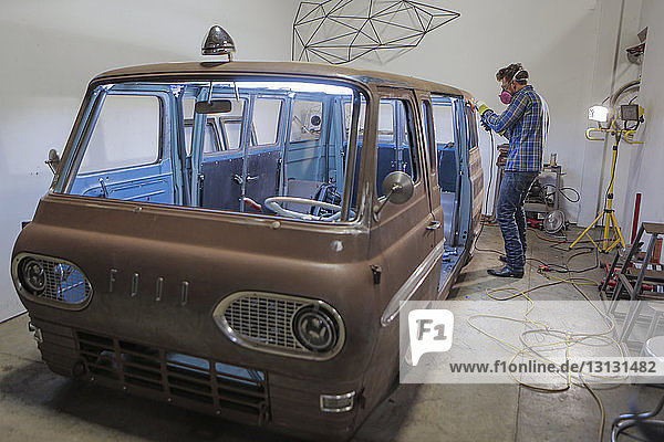 Side view of engineer polishing van with angle grinder in industry