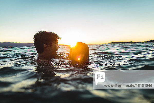 Junges Paar schwimmt im Meer gegen den Himmel