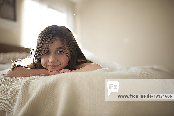 Porträt eines lächelnden Mädchens  das zu Hause auf dem Bett liegt
