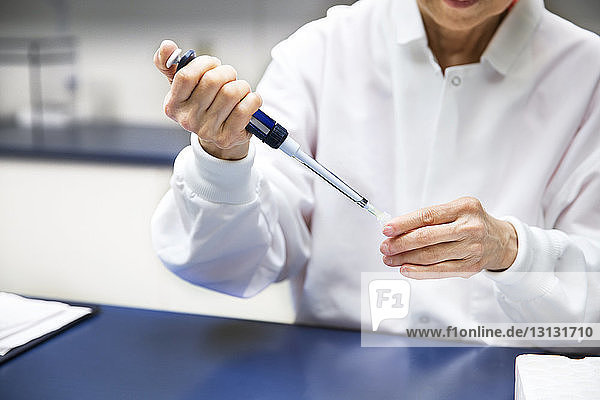Leitende Wissenschaftlerin gießt Chemikalie durch eine Pipette im Labor