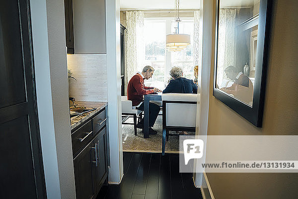 Älteres Ehepaar sitzt im Büro des Finanzberaters und wird durch die Tür gesehen