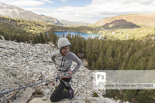 Happy woman climbing mountain against forest