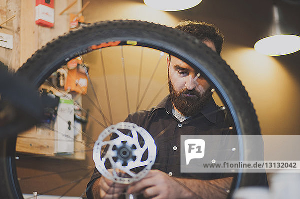 Männlicher Mechaniker repariert Reifen in Fahrradwerkstatt
