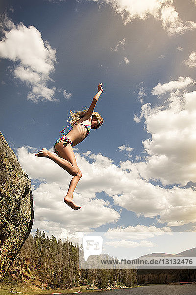 Low angle view of girl diving in lake against sky