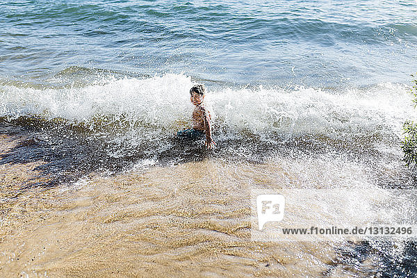 Junge ohne Hemd  der sich an sonnigen Tagen am Strand amüsiert