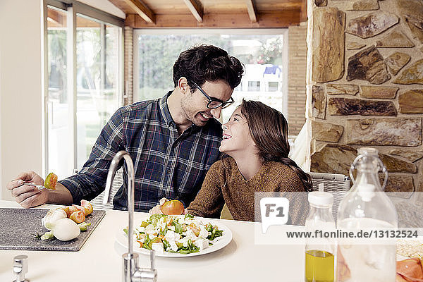 Glückliche Vater und Tochter essen Salat  während sie am Tisch sitzen