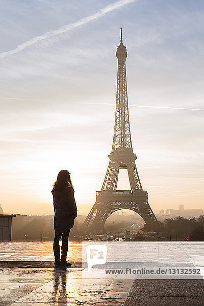 Silhouette woman looking at Eiffel Tower against sky