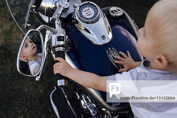 Hochwinkelansicht eines kleinen Jungen,  der im Sitzen auf einem Motorrad wegschaut