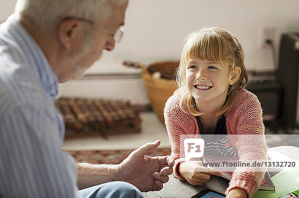 Enkelin sieht Großvater an  während sie auf dem Sofa sitzt