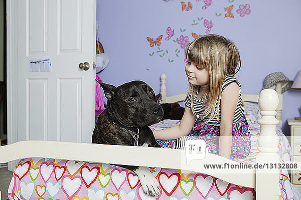 Cute girl with dog on bed at home